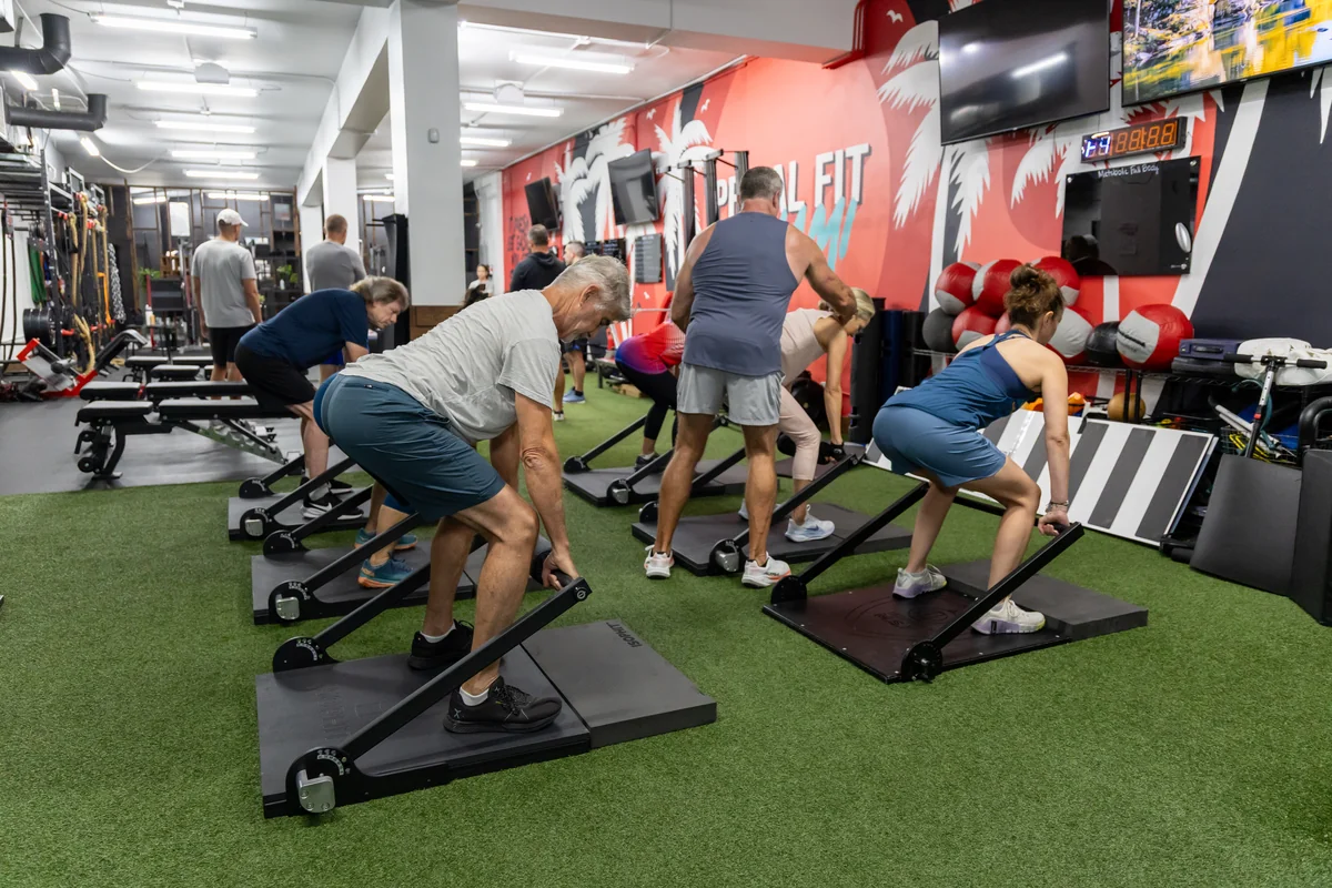 Adults 50+ doing small group ISOPHIT isometric strength training at Primal Fit Miami